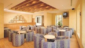 A spacious lounge area with multiple seating options, a bar with a variety of bottles, and a television mounted on the wall. - Hotel Sevilla (Mexico City)