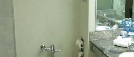 A bathroom with a toilet, a sink, and a mirror. There are two shelves with towels above the toilet.