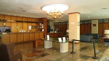 A lobby with a reception desk, a chandelier, a blue sofa, and a coffee table.