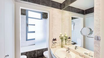 A modern bathroom with a large mirror, a sink, and a toilet.