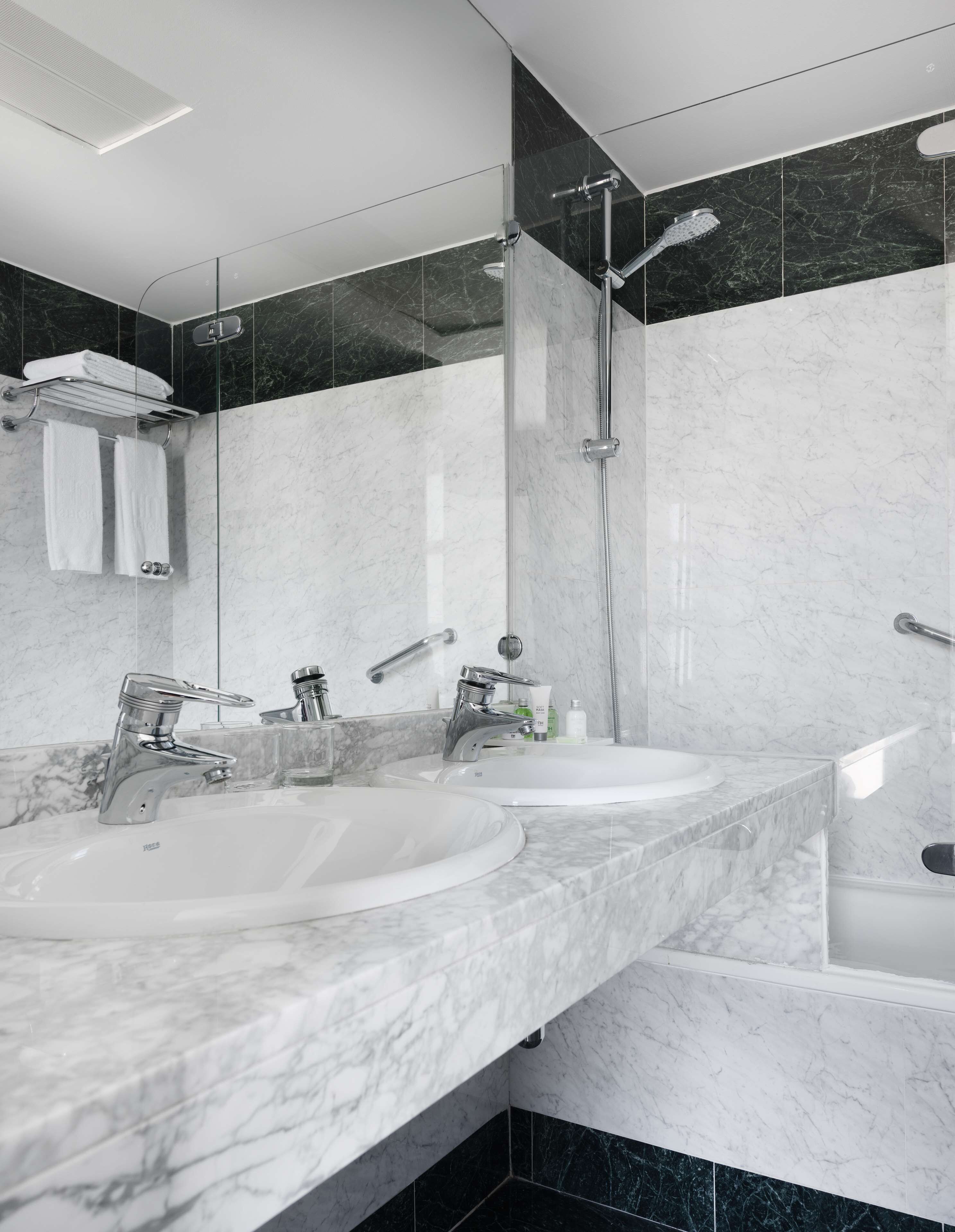 A modern bathroom with two sinks, a shower, and a glass-enclosed shower area.