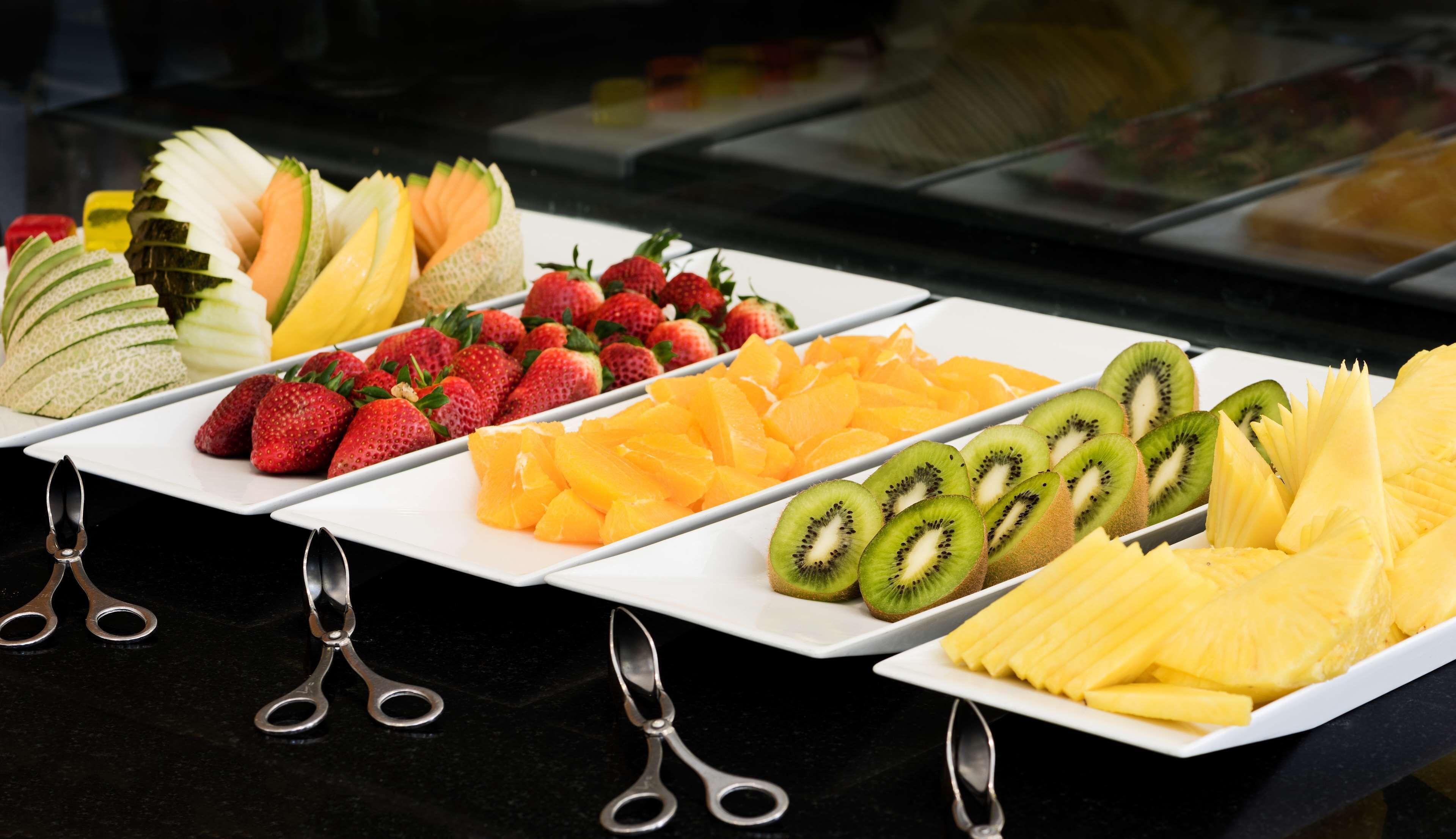 Eine Auswahl geschnittener Früchte, darunter Erdbeeren, Kiwis, Ananas und Melone.