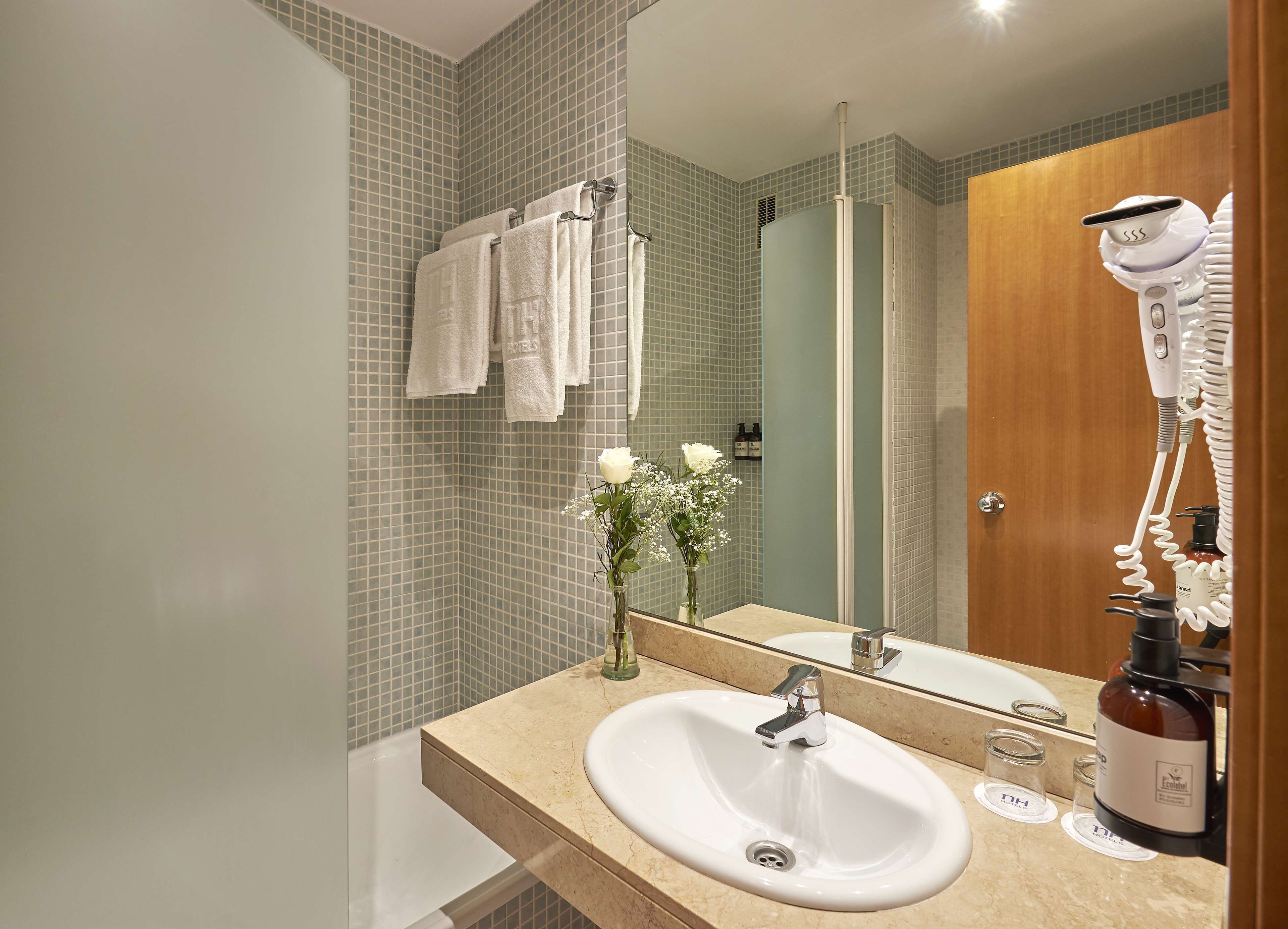 A modern bathroom with a sink, mirror, and a hairdryer on the counter.