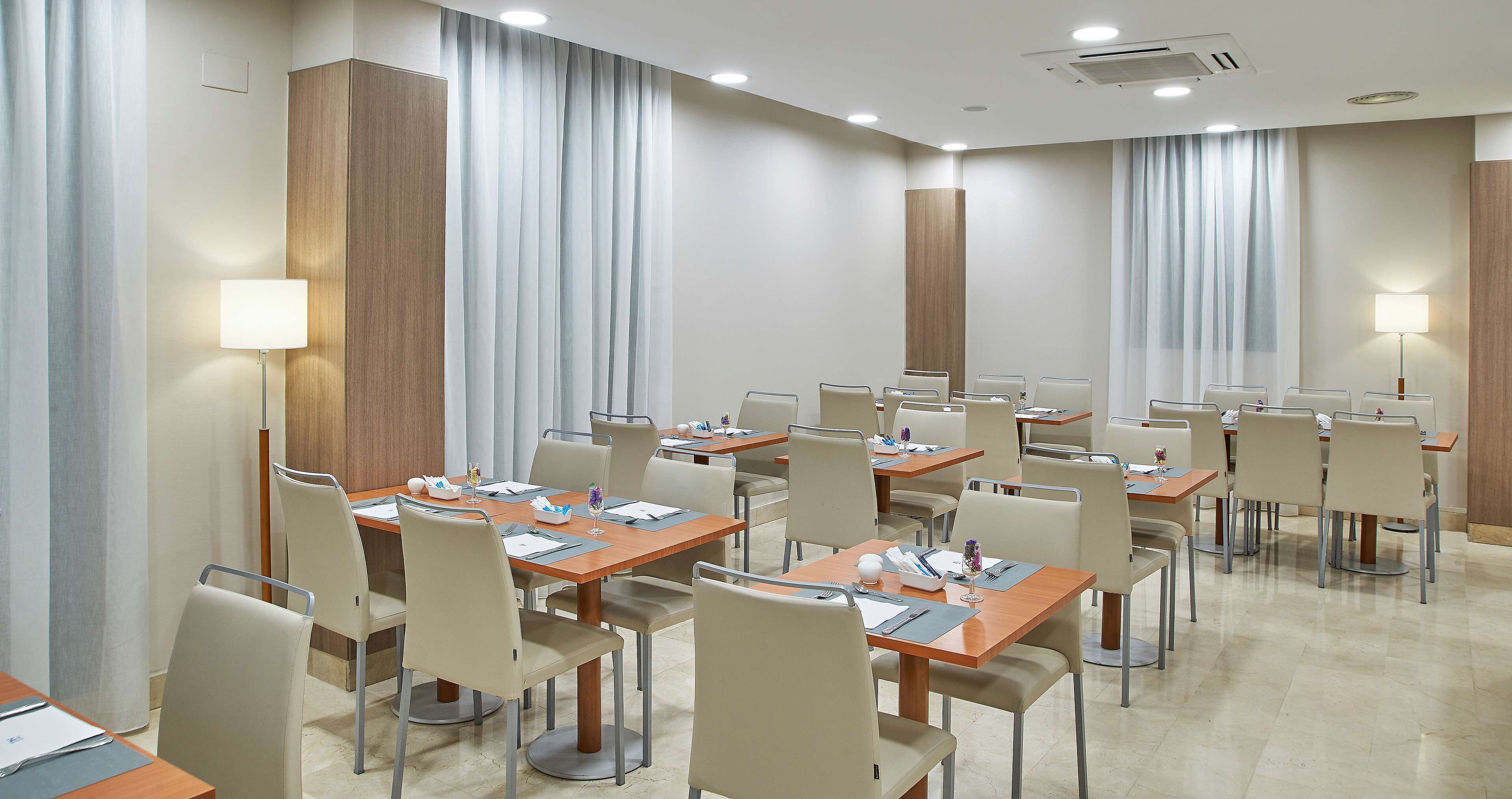 Une salle de conférence d’hôtel dotée de plusieurs tables et chaises, ainsi que de plaques nominatives, de stylos et de blocs-notes.