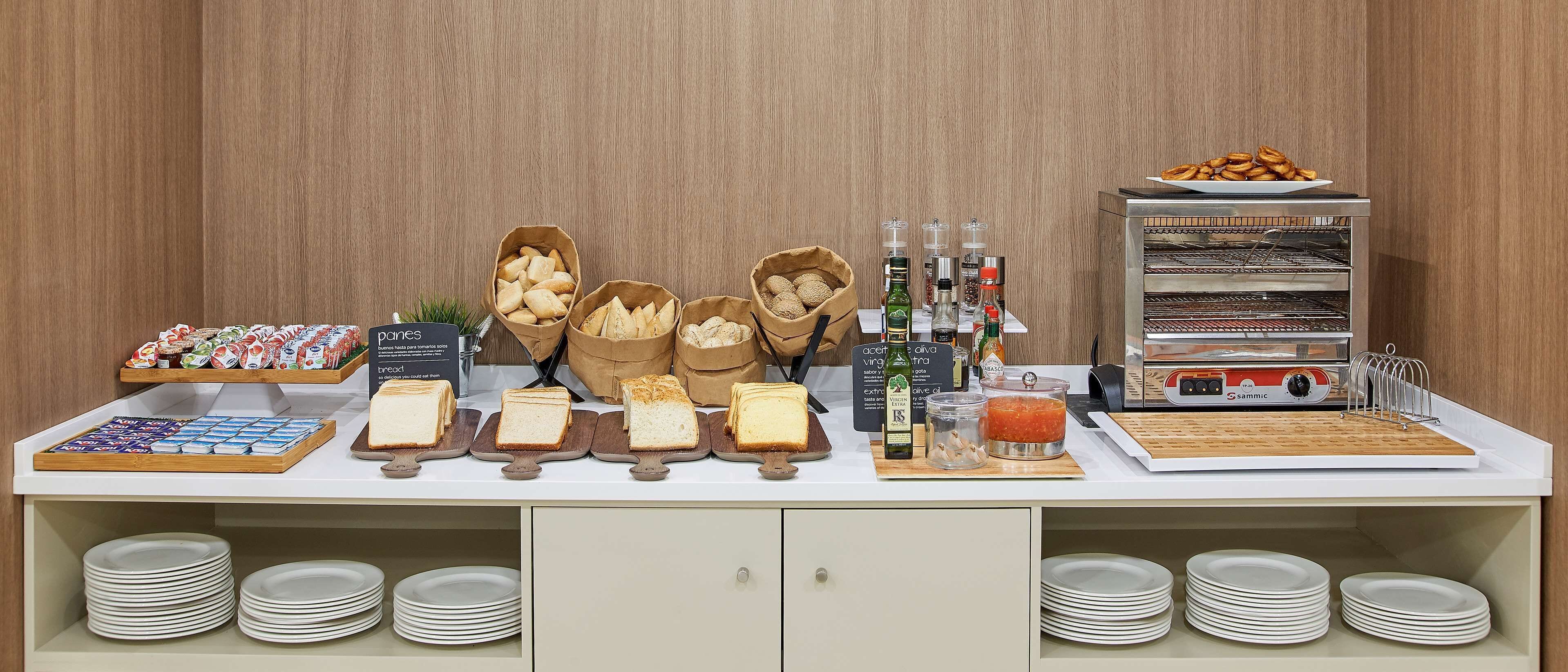 A buffet setup with various food items, including bread, pastries, and condiments.