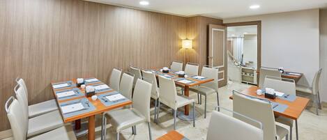 A conference room with multiple tables and chairs, equipped with nameplates, notepads, and pens.