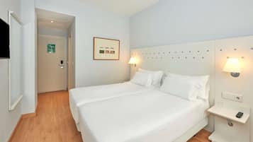 Une chambre d’hôtel avec un lit double, des lampes de chevet, une petite table de chevet et un tableau encadré au mur.