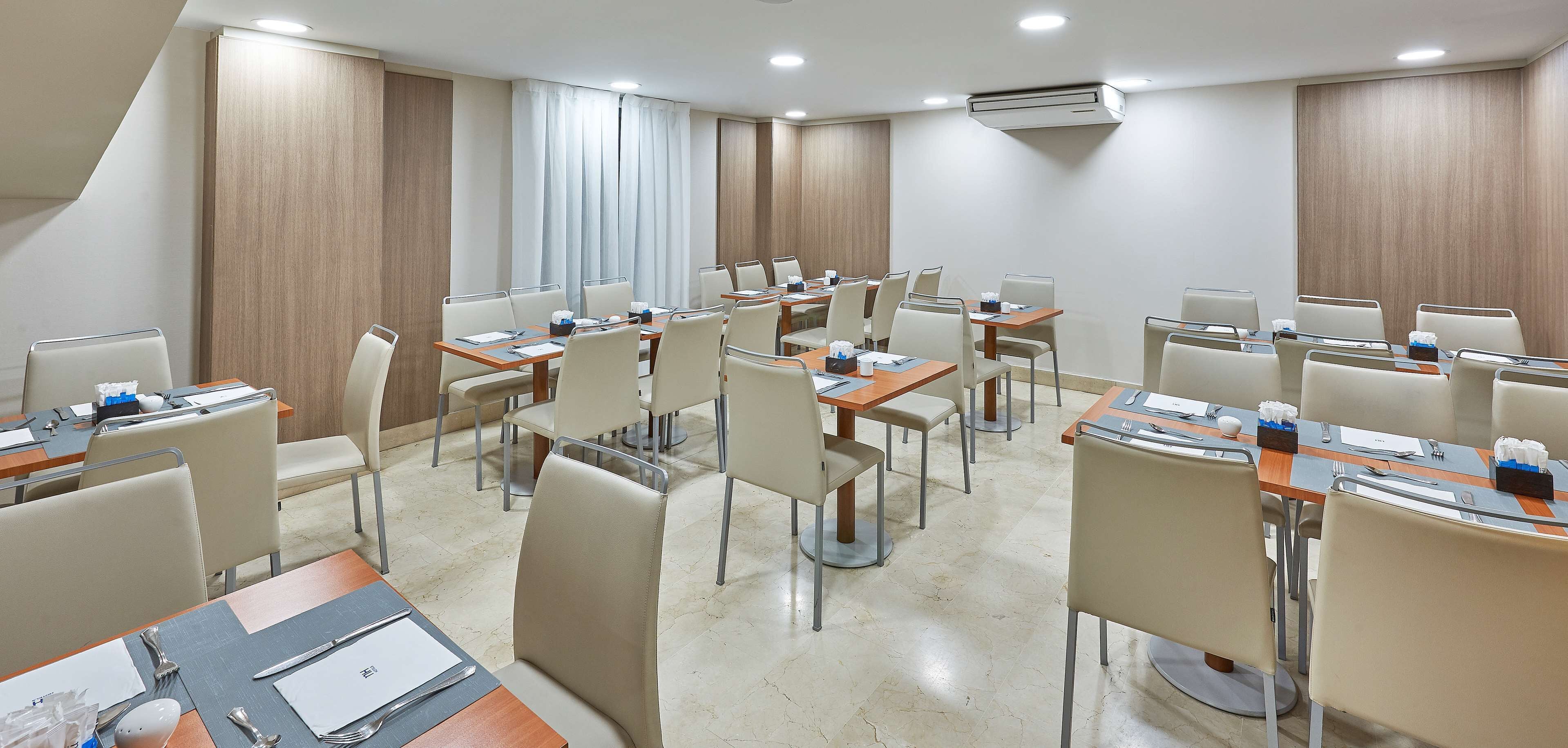 A conference room with multiple tables and chairs, equipped with nameplates, water bottles, and notepads.