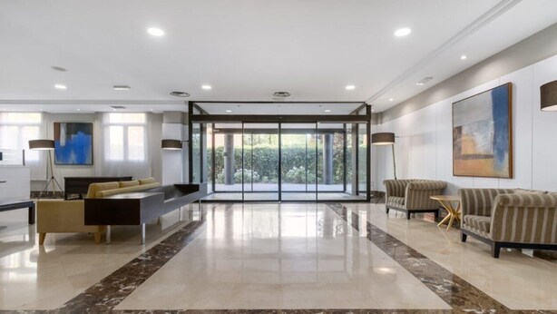 A spacious living area with a modern design, featuring a sofa, a coffee table, and a dining table. - Crisol Leganés (Leganes)