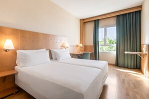 A hotel room with two beds, a desk, and a window with curtains. - Crisol Leganés (Leganes)