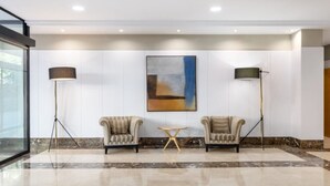 A lobby with two armchairs, a small round table, and two floor lamps. - Crisol Leganés (Leganes)