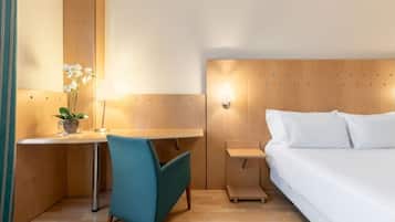 Relax in a stylish room with a single bed, desk, and potted plant.
