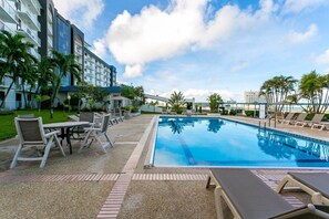 Relax by the pool surrounded by comfortable lounge chairs and a table, with stunning views of the surrounding landscape.