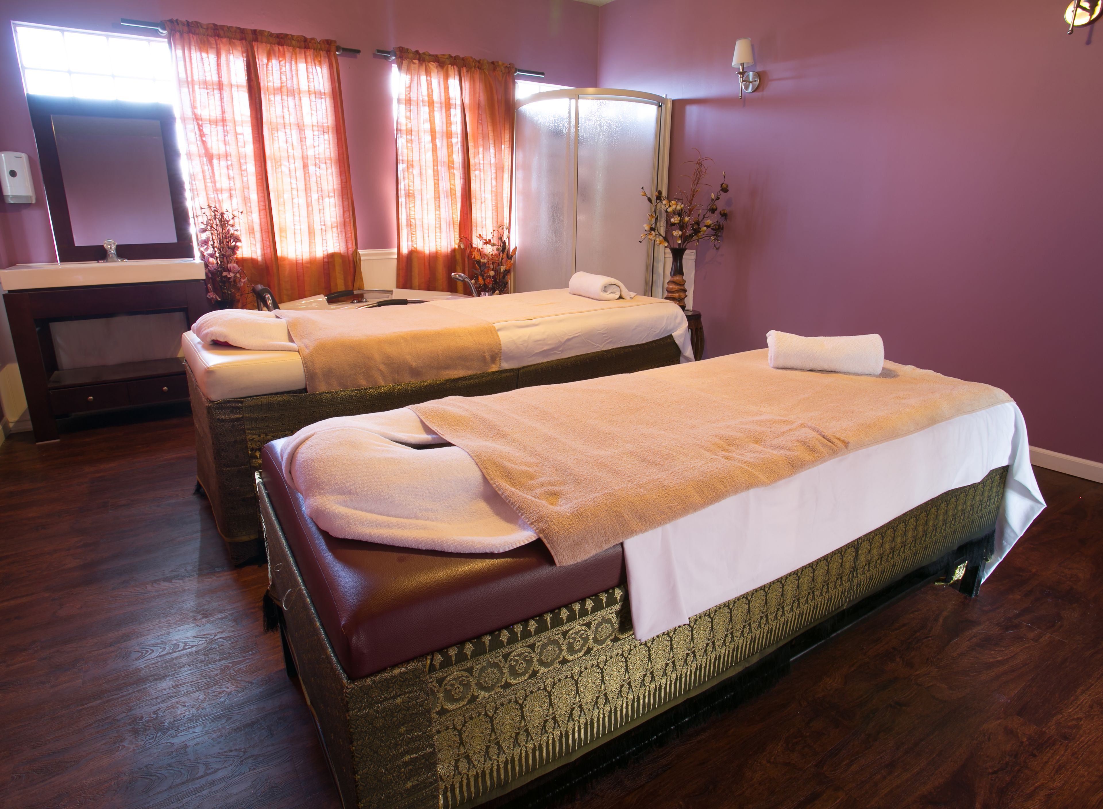 A hotel room with two beds, a large mirror, and a vase with flowers.
