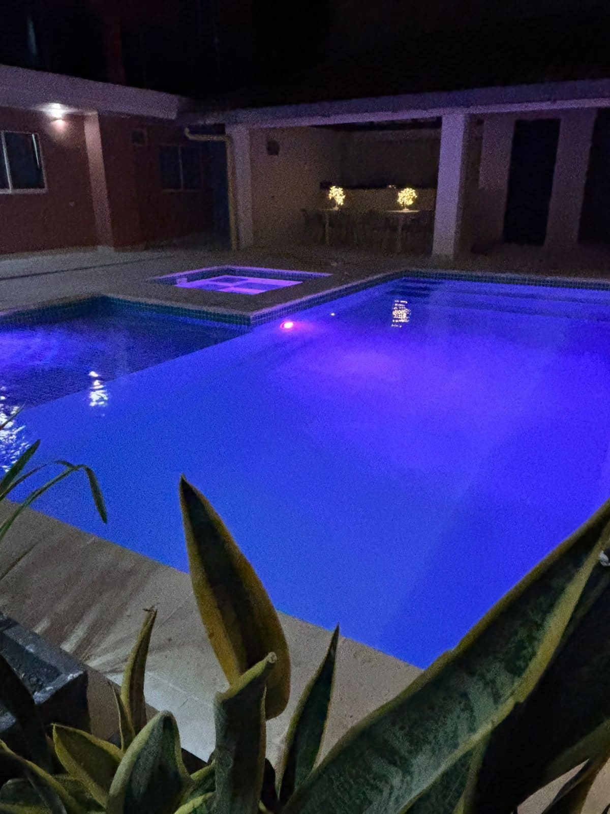 A swimming pool with a blue tint, surrounded by a building with a tiled exterior.