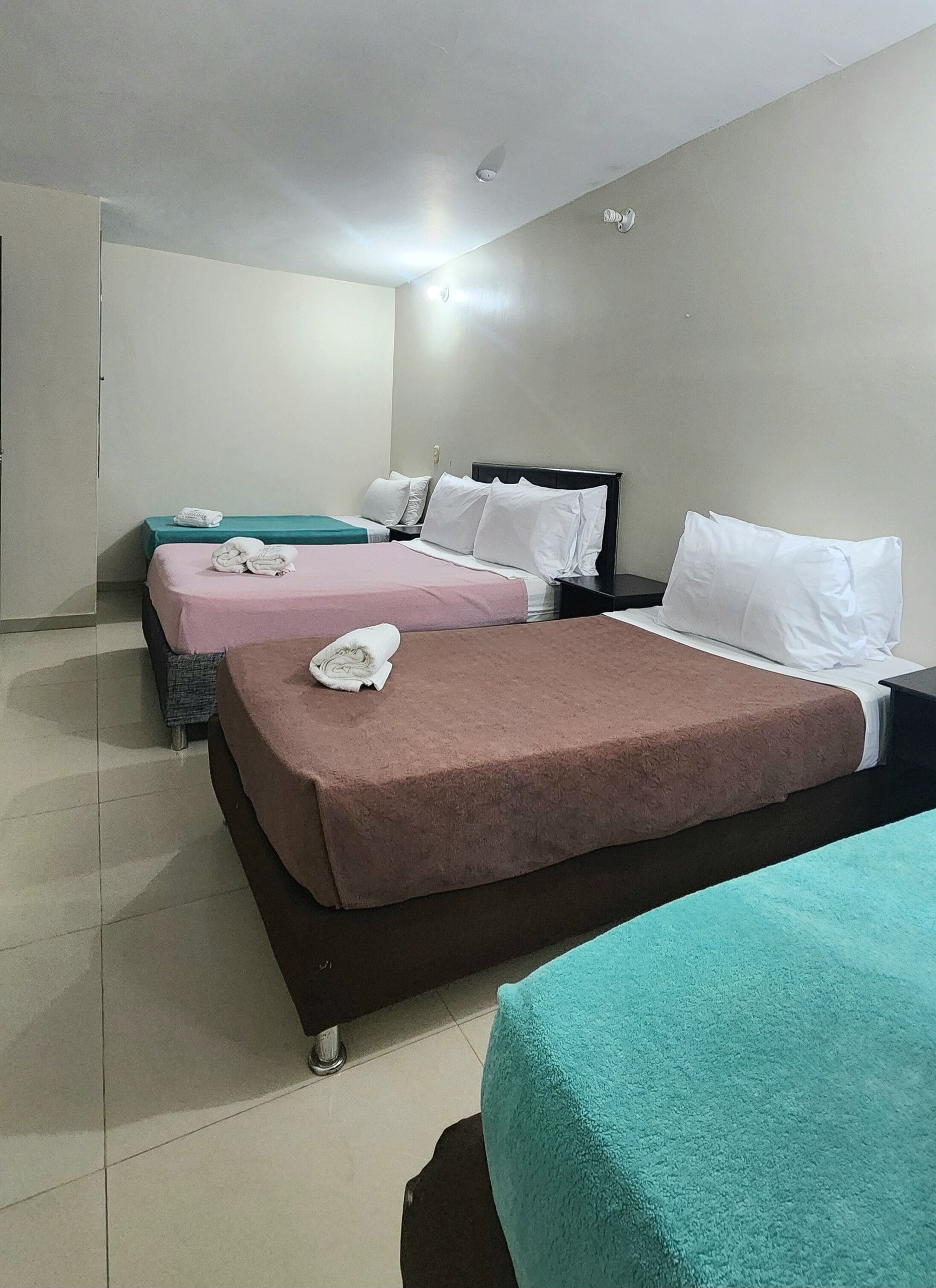 Una habitación de hotel con dos camas, un armario y suelo de baldosas.