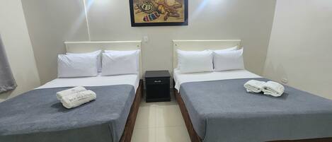 A hotel room with two beds, white bedding, a small black nightstand, and a painting on the wall.