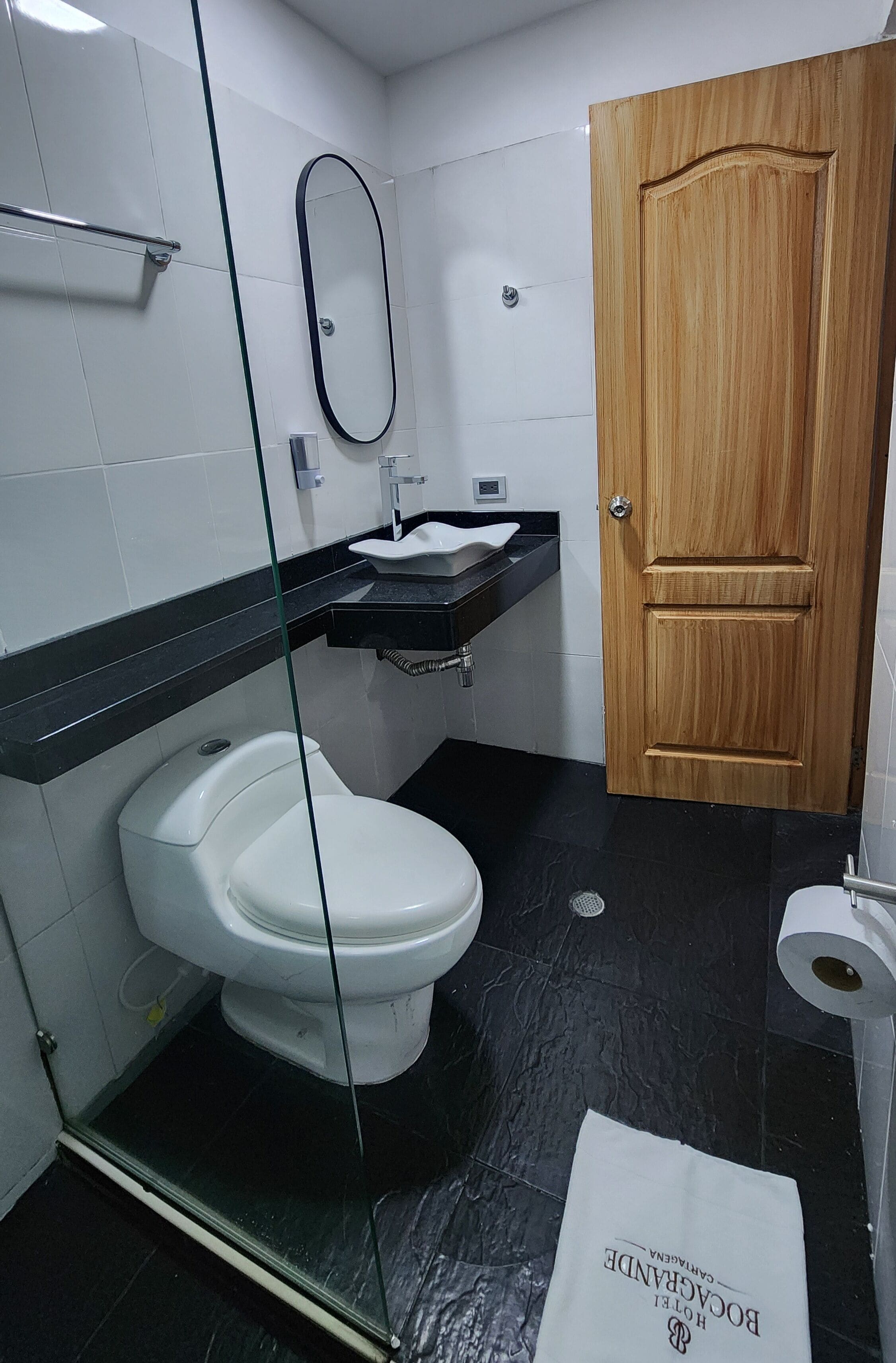 A bathroom with a toilet, a sink, a mirror, and a wooden door.