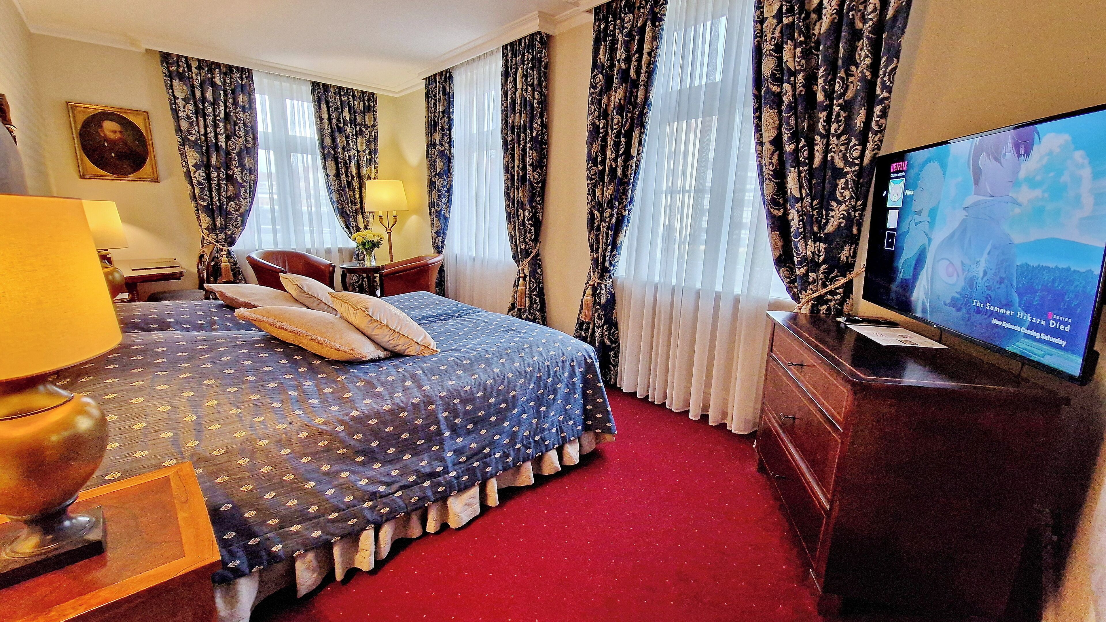A hotel room with a bed, a television, a desk, and a chair.