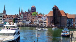 Un port où sont amarrés des bateaux, une église imposante dotée d’un clocher élevé, et des bâtiments traditionnels aux toits rouges.