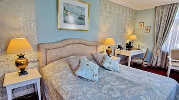 A hotel room with a bed, two bedside tables with lamps, a desk with a telephone, and a chair.