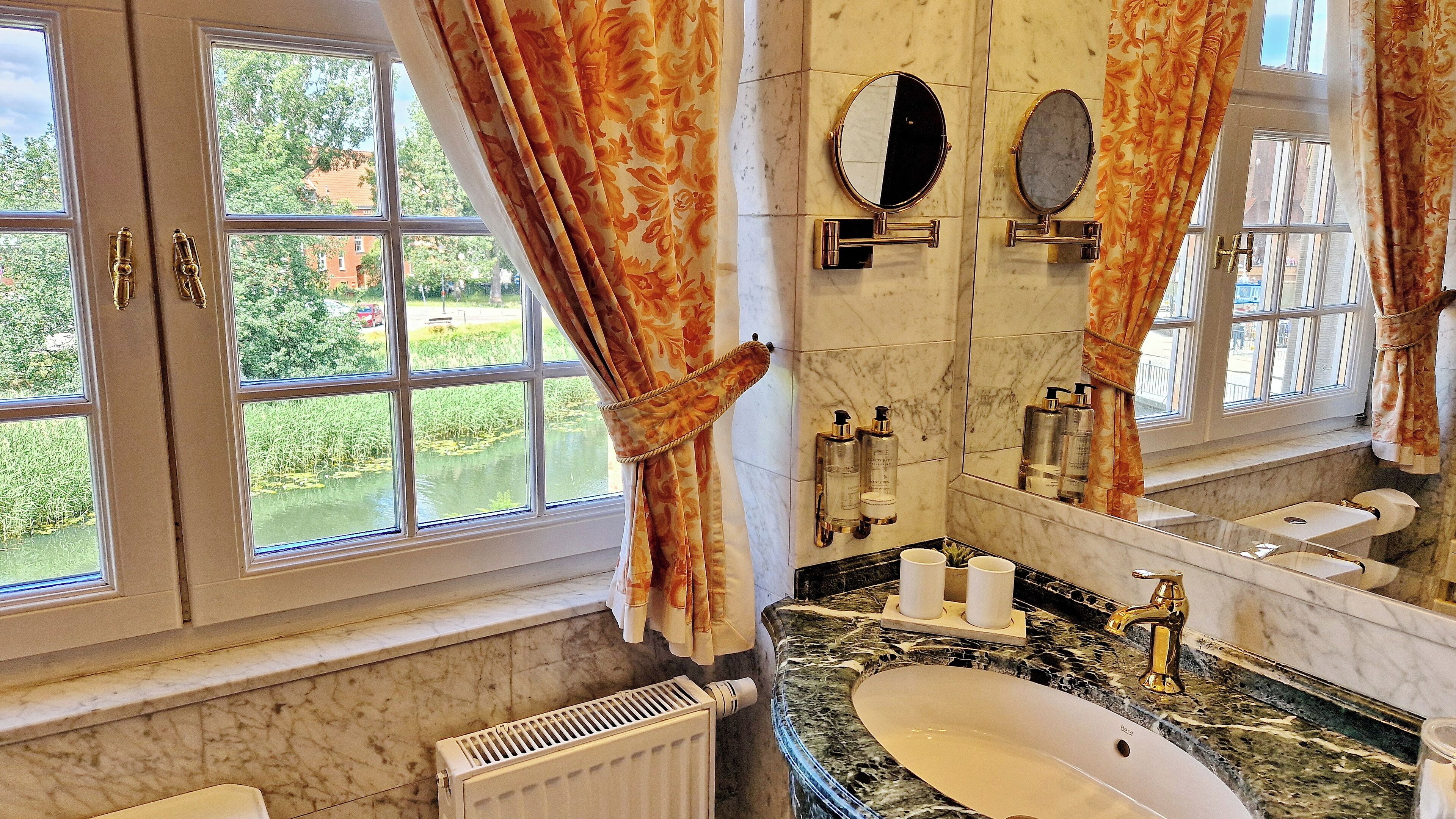 A bathroom with a large window, a marble sink, and a mirror.