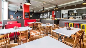 Un interior de restaurante con cabinas, mesas y una zona de bar.
