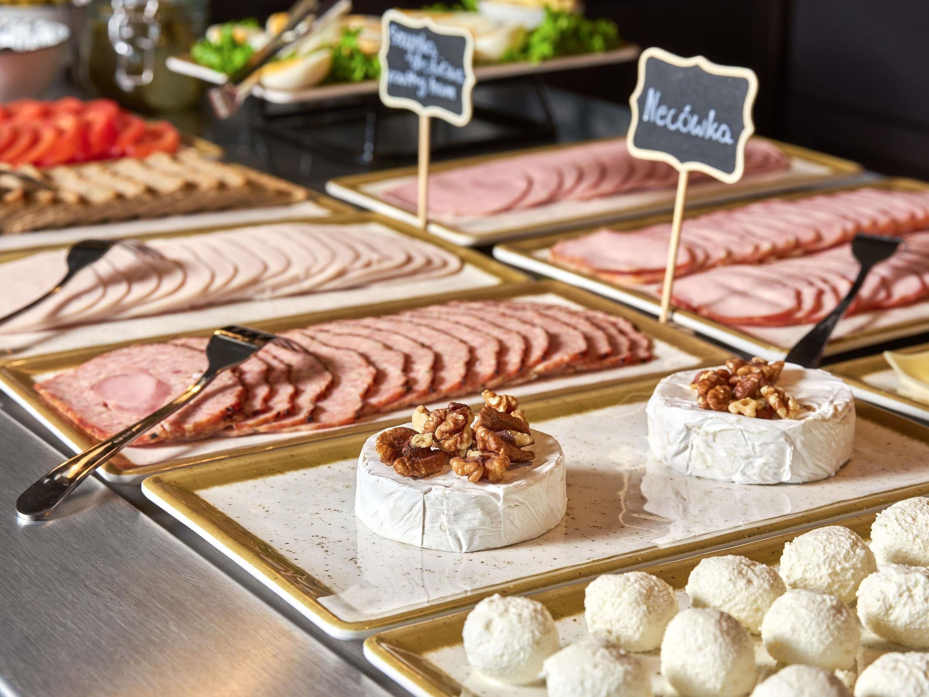 Un bufé con diversos alimentos, como jamón en rodajas, queso y productos de pastelería.