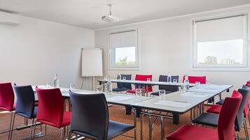 A conference room with a whiteboard, projector, and red and black chairs.