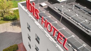 Un hotel con paneles solares en la azotea y un letrero rojo llamativo.