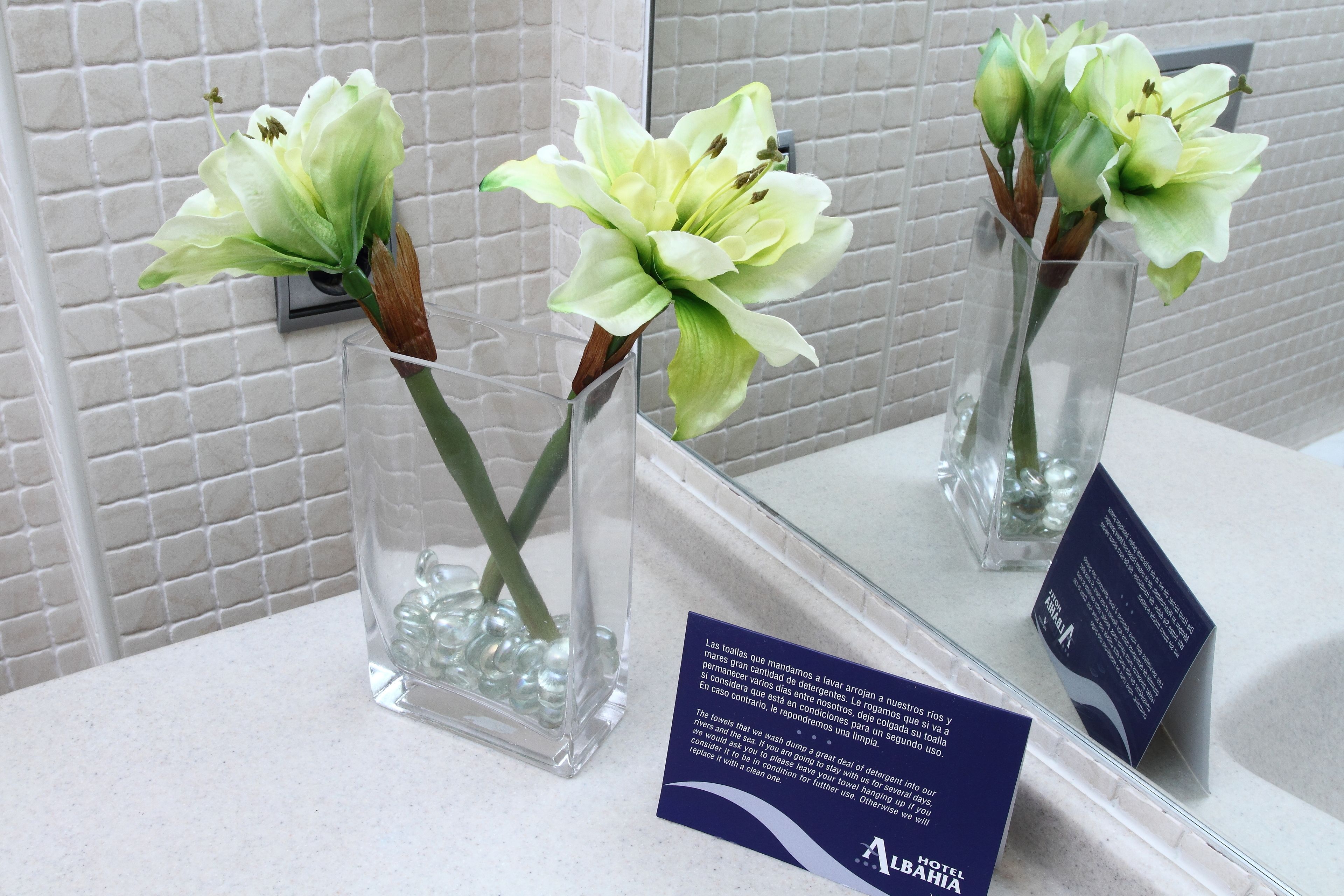 Three clear glass vases with artificial flowers on a counter.