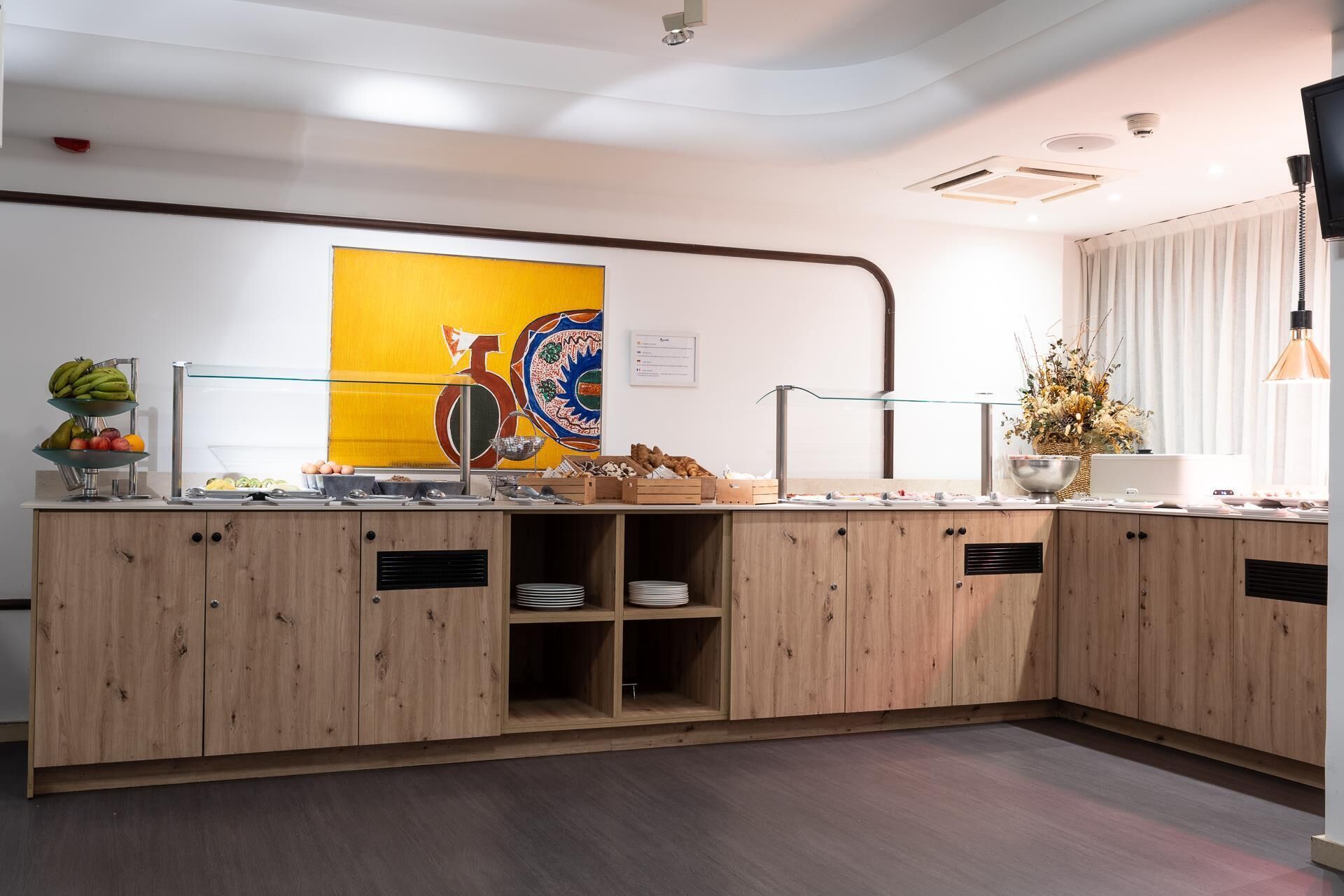 Una cocina moderna con armarios de madera, una exposición de frutas y un adorno de pared.