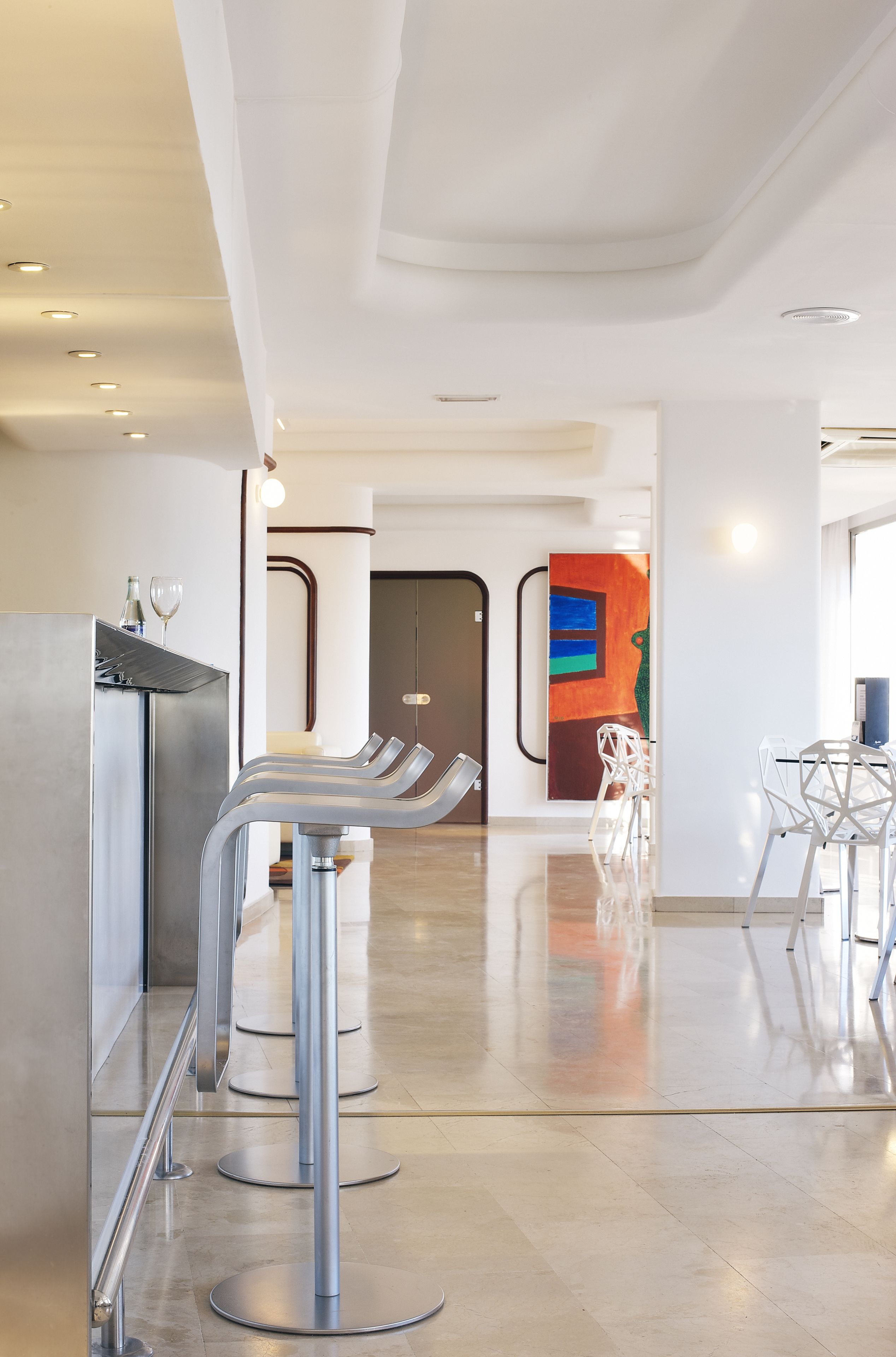 Een modern interieur met een bar, zitplaatsen en een kleurrijk abstract schilderij.