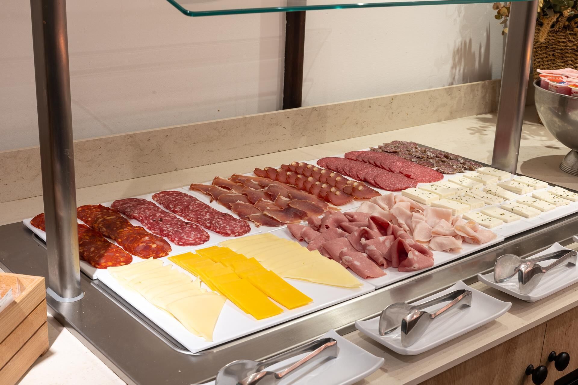 A deli counter with various types of cured meats and cheeses displayed on trays.