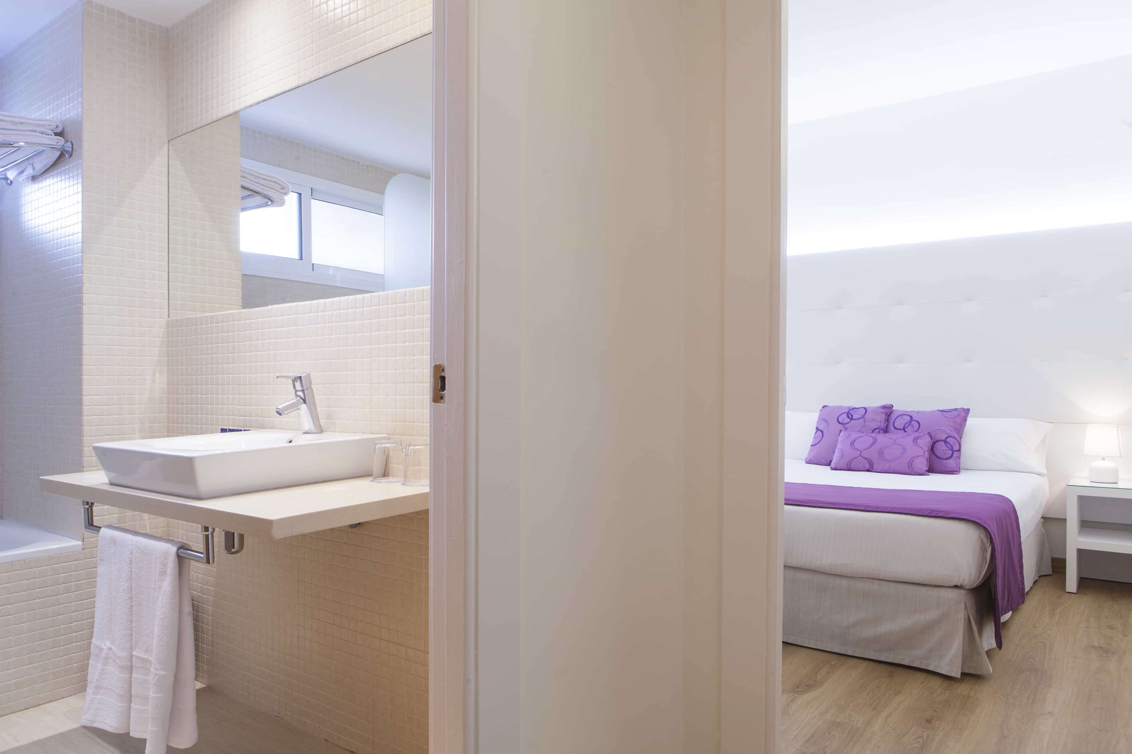 Ein modernes Badezimmer mit großem Spiegel, weißem Waschbecken und Handtuchhalter.