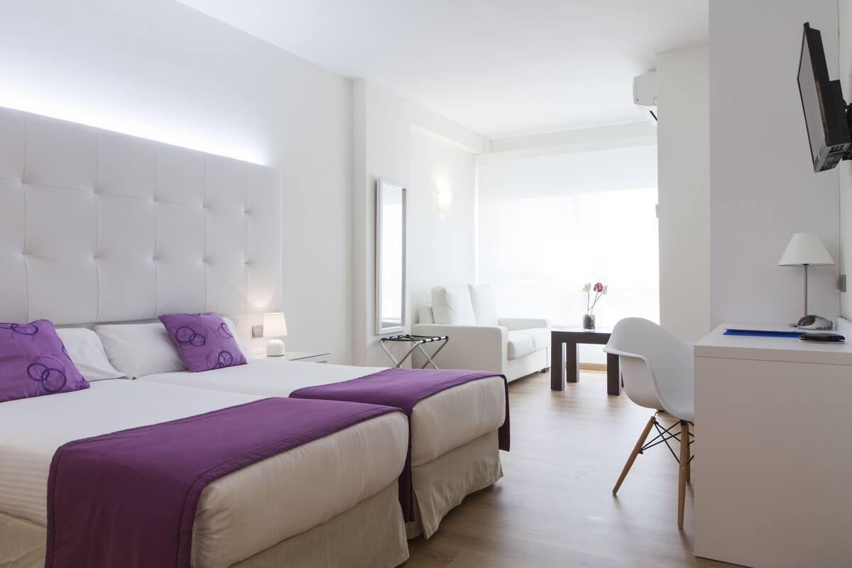 A hotel room with a large bed, two bedside tables, a desk, and a chair.