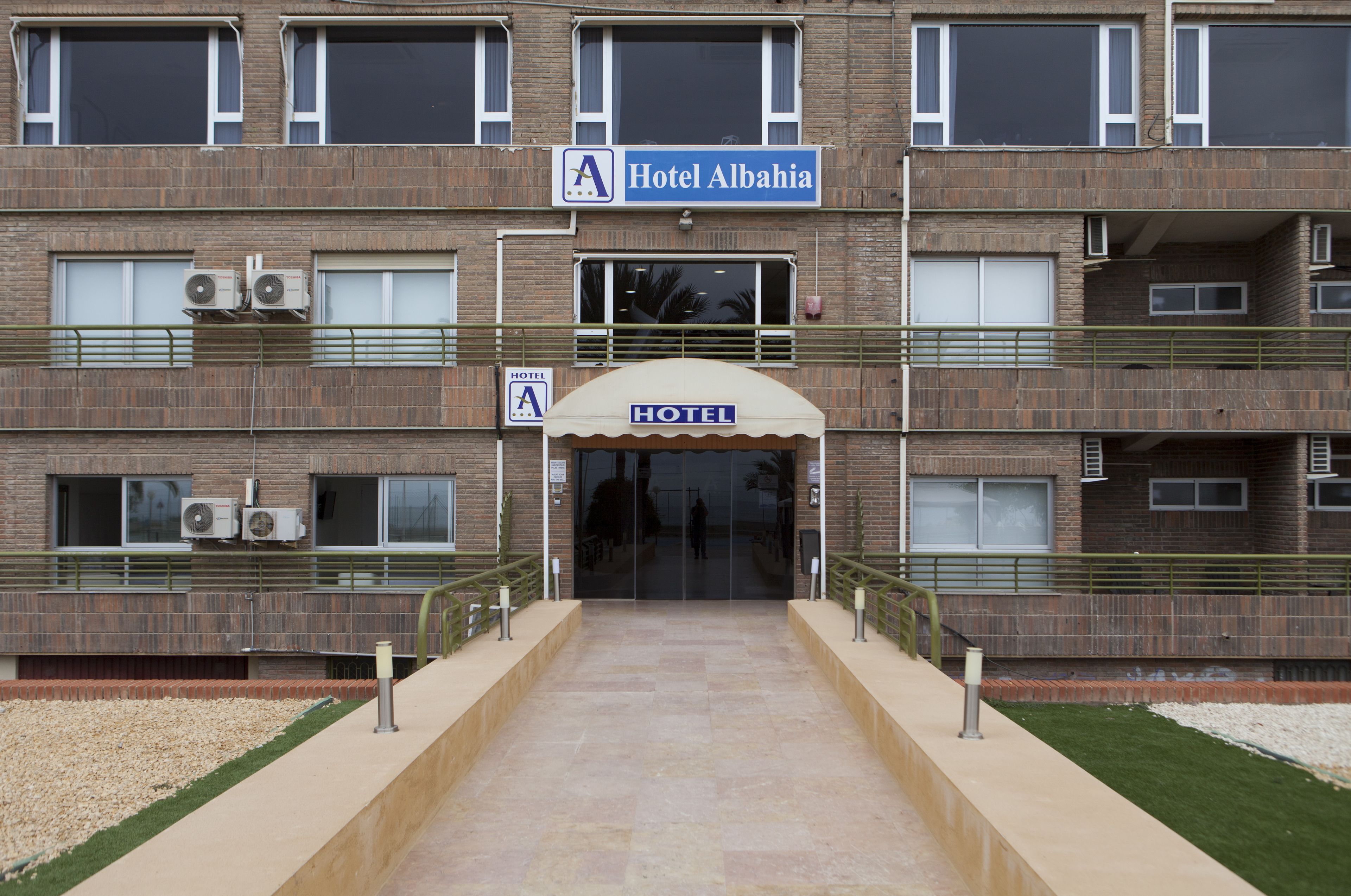 Entrada de un hotel con un cartel que dice 'Hotel Alba'.