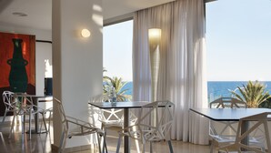 A modern dining area with a view of the sea, featuring a round table and white chairs. - Hotel Albahia (Alicante)