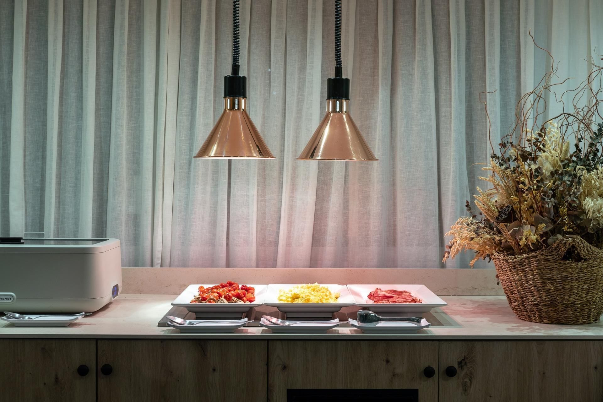 Una encimera de cocina con una exhibición de alimentos, una cafetera y una planta decorativa.