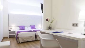 Una camera d'albergo moderna con un letto, un comodino, una scrivania, una sedia e un vaso con fiori.