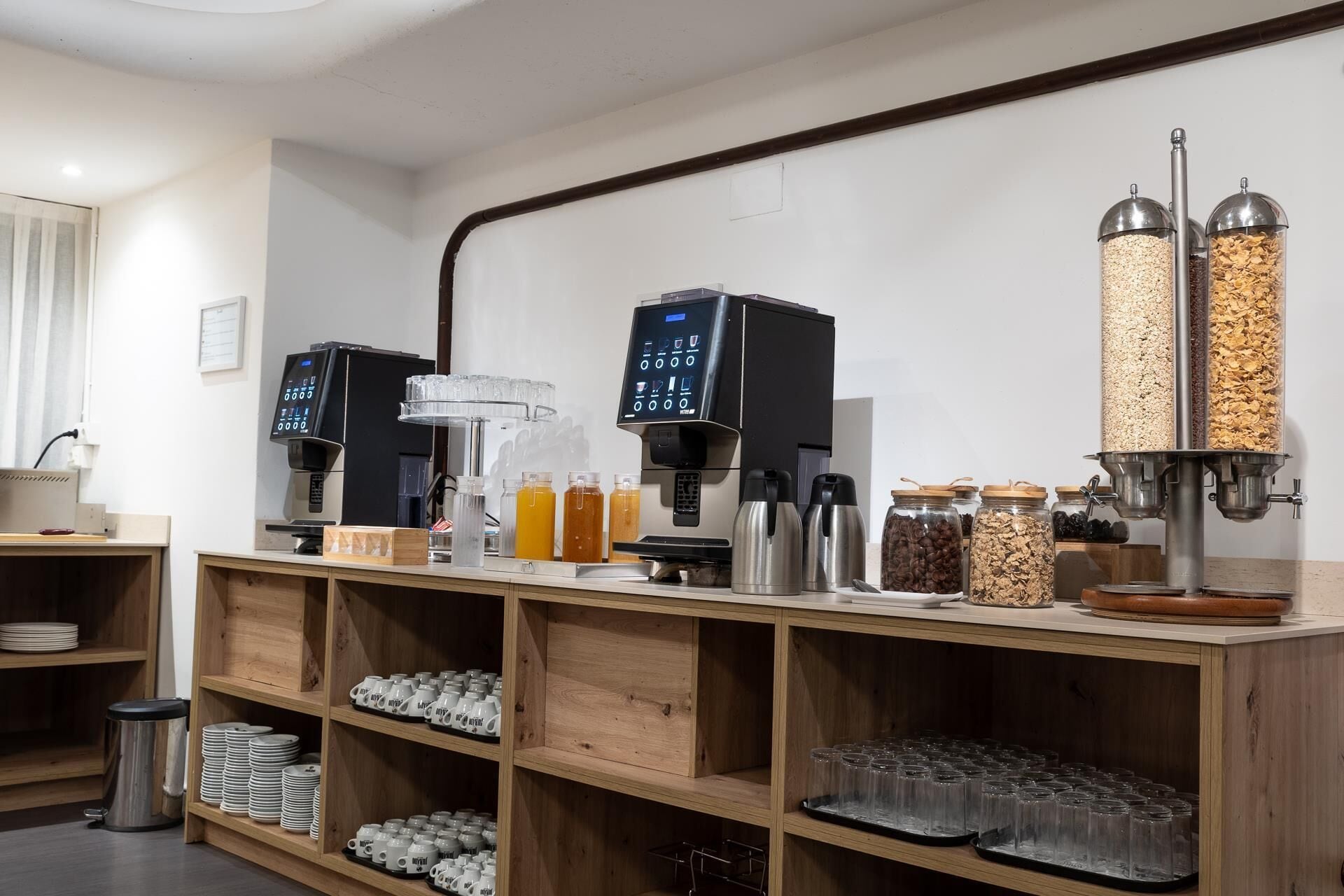 A coffee station with multiple coffee machines, a juice dispenser, and various food containers.