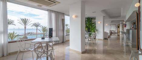 Habitación de hotel moderna con zona de comedor, vistas al mar y área de cocina.