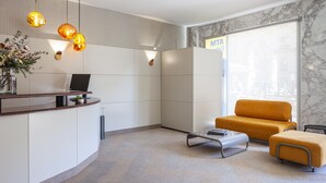 Ein moderner Empfangsbereich mit einer gebogenen Theke, einer Couch und Pendelleuchten.