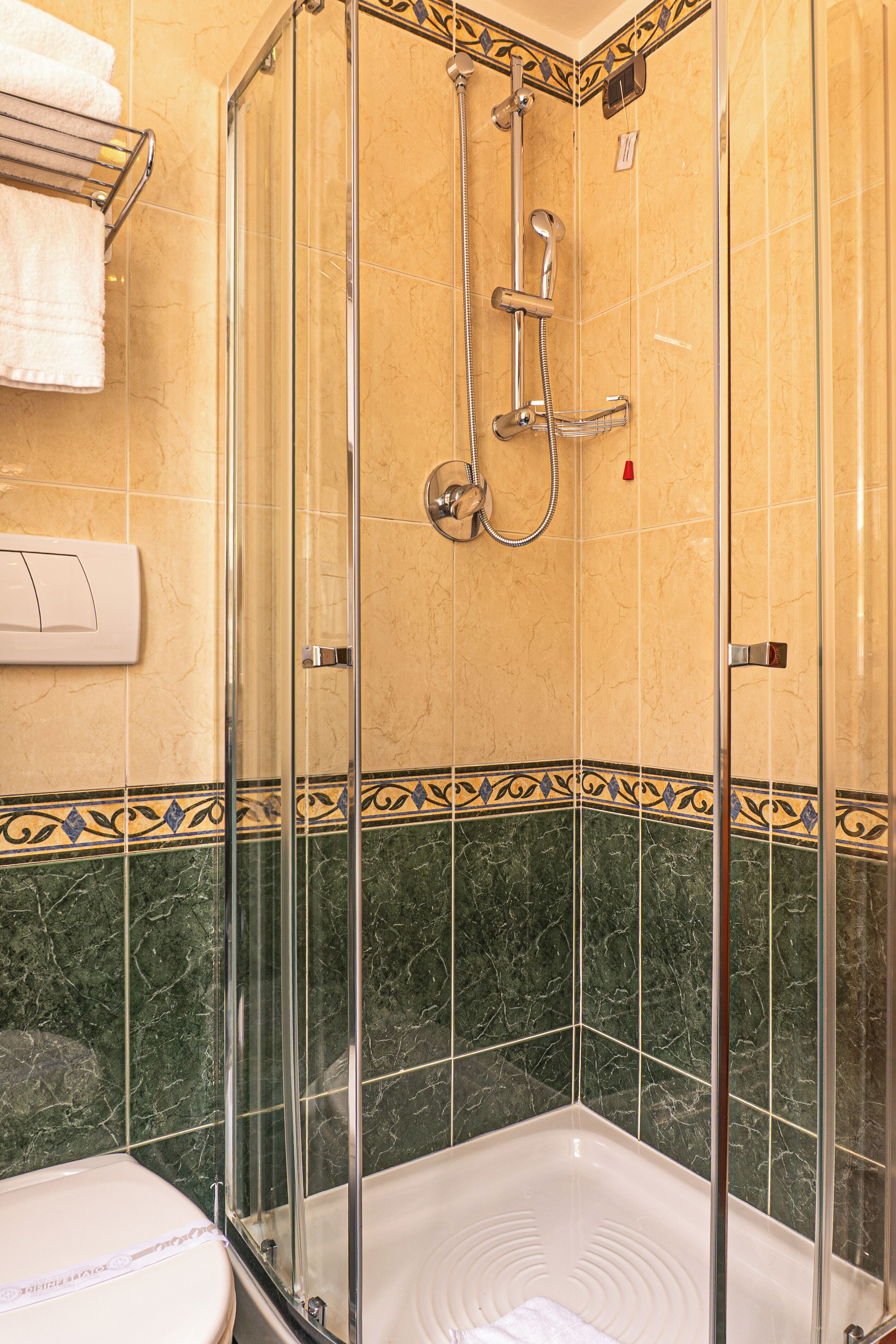Cabina doccia in vetro con soffione a mano e rubinetto erogatore manuale.