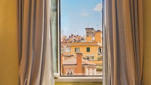 Una ventana con cortinas, mostrando vistas de edificios y un cielo despejado.