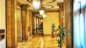 Un pasillo con piso estampado, columnas y un candelabro.