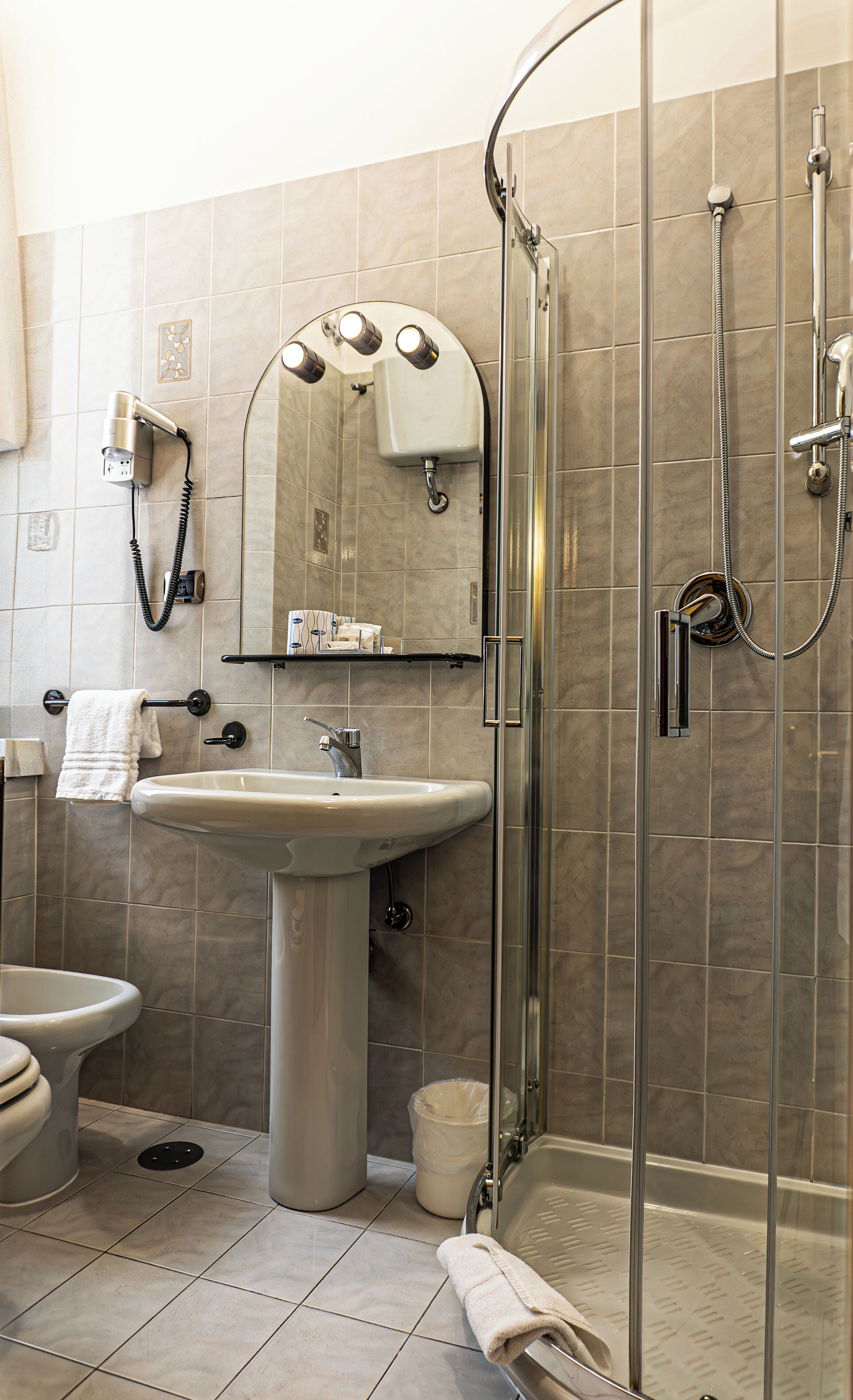 Un baño moderno con lavamanos, espejo e inodoro con ducha.