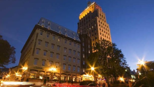 Um hotel de vários andares com um edifício de canto imponente e uma rua bem iluminada em primeiro plano.