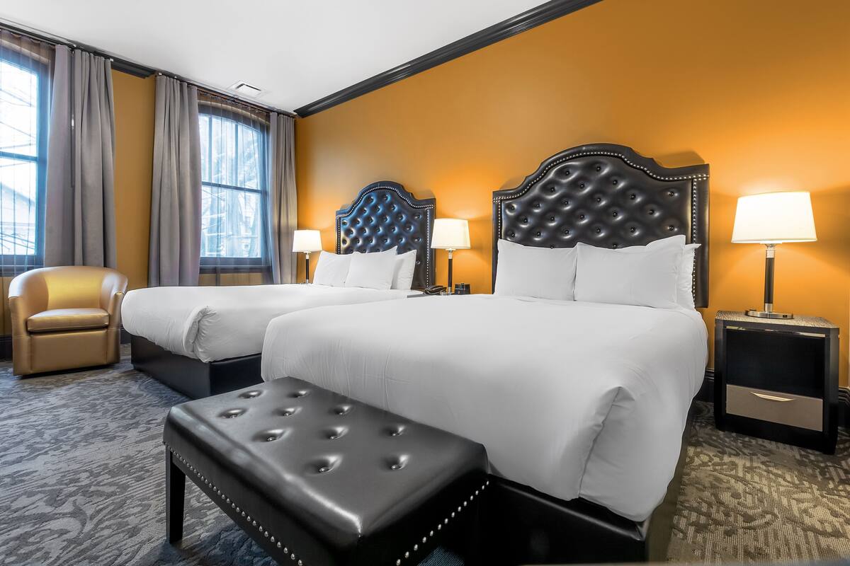 A hotel room with two beds, a sofa, a chair, and a small table.
