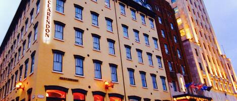 Un hotel con varios pisos, un letrero destacado que dice "Hotel Clarendon" y un edificio grande al fondo.